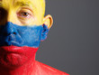 Man face painted with colombian flag, sad expression.
