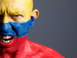 Man face painted with colombian flag, angry expression.