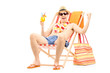 Happy young man enjoying a cocktail and sitting on a beach chair
