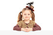 Pretty little girl posing behind white panel