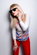 Beautiful and young blonde in sunglasses and red jeans
