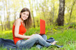 Beautiful girl sitting on the grass with a notebook