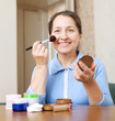 mature woman puts facepowder