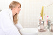 Photo: Woman looking into bathroom mirror Woman looking into bathroom mirror