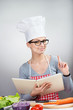 Photo: Smiling woman with cookbook raising index finger up Smiling woman with cookbook raising index finger up