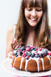 Woman smiling at glazed cake with mixed berries