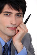 Pensive man holding pen to mo face