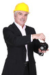 An architect putting a coin in a piggy bank.