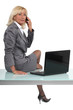 Photo: Blond executive sat on desk making call Blond executive sat on desk making call