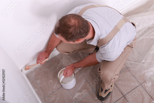 Photo: Man painting a wall white Man painting a wall white