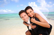 Groom carrying bride on his back at the beach