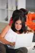 Foto: Teenage girl using a laptop at home with friends Teenage girl using a laptop at home with friends