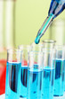 Laboratory pipette with drop of color liquid over glass test