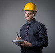 young builder in a building helmet with a notebook in hands