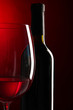 Glass of wine with bottle on bright red background