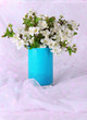 Flowering branches in vase on light fabric background