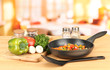 Vegetable ragout in pan,  on wooden table on bright background