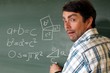 Lehrer mit Formel an Tafel zeigt Schülern Geometr