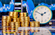 Stacks of golden coins, clock and the financial chart as backgro