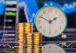 Downtrend stacks of golden coins, clock and the financial chart