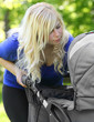 Young mother with baby stroller  walking in the park.