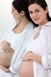 Pregnant woman hugging her belly while leaning against a mirror