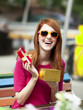 Style redhead girl with gift sitting on the bench in the cafe