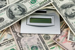 One hundred dollar  lying on the calculator