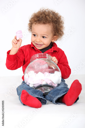 Photo: Little boy eating marshmallows from jar Little boy eating marshmallows from jar