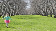 Little cheerful girl runs on park in the direction of the camera