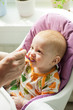 Hungry baby eating first solid food from spoon with pleasure