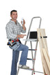 Photo: Carpenter standing by a ladder with a mobile telephone Carpenter standing by a ladder with a mobile telephone