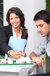 Foto: Female architect showing model to man Female architect showing model to man