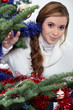Photo: Young woman stood by Christmas tree Young woman stood by Christmas tree