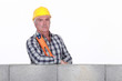 Mason with spirit-level stood by wall