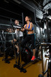 elliptical walker trainer man and woman at black gym