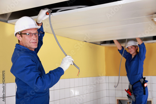 Photo: Two electricians working on false ceiling Two electricians working on false ceiling