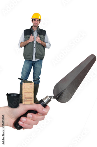 Photo: Bricklayer standing on a hand holding a trowel Bricklayer standing on a hand holding a trowel