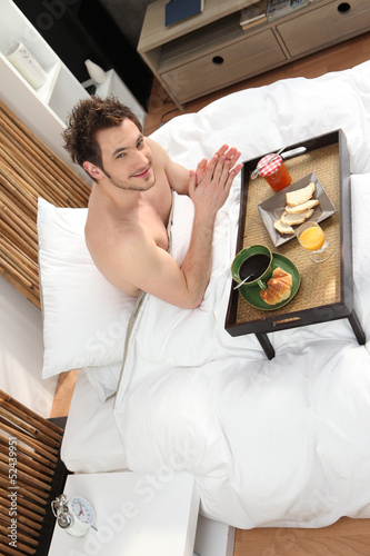 Photo: Man having breakfast in bed Man having breakfast in bed