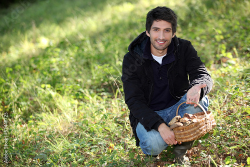 Photo: Man knelt by basket of mushrooms Man knelt by basket of mushrooms