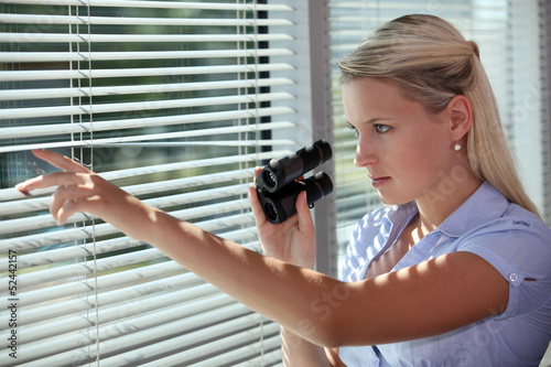 Photo: woman looking through the blinds with binoculars woman looking through the blinds with binoculars