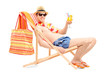 Smiling young male on a beach chair drinking cocktail