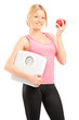 Young smiling female holding a weight scale and a red apple