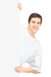 Young smiling male patient in a hospital gown posing behind a pa