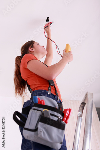 Photo: Woman measuring a wire's electrical current Woman measuring a wire's electrical current