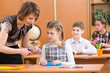 Schoolkids work at labour lesson. Teacher helping pupil.