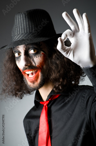 Photo: Joker personification with man in dark room Joker personification with man in dark room