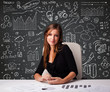 Businesswoman sitting at desk with business scheme and icons