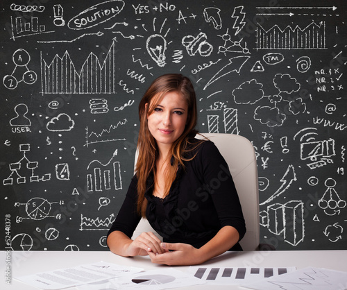 Photo: Businesswoman sitting at desk with business scheme and icons Businesswoman sitting at desk with business scheme and icons