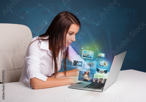 Photo: Beautiful girl sitting at desk and watching her photo gallery on Beautiful girl sitting at desk and watching her photo gallery on